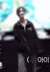 a woman in a black jacket is dancing in front of a sign that says ' aoi ' on it
