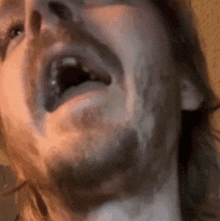 a close up of a man 's face with a beard and his mouth open .