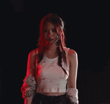 a woman in a white tank top is standing in the dark