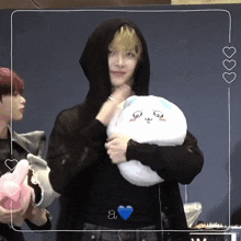 a man in a black hoodie holds a stuffed animal