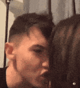 a man and a woman are kissing in front of a curtain .