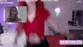 a woman in a red top is dancing in front of a microphone on a twitch stream