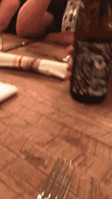 a bottle of beer sits on a wooden table next to a napkin and fork