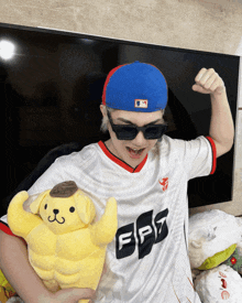 a person wearing a blue hat and sunglasses holds a stuffed animal with the letter fpz on it