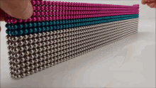 a row of pink blue and silver beads are stacked together
