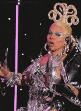 a woman in a silver and gold costume is holding a microphone in front of a tumblr logo
