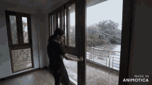 a woman opens a sliding glass door with the words made in animotica below her