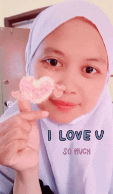 a woman in a white hijab is holding a heart in front of her face with the words i love u so much written below her