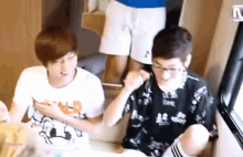 two young men are sitting next to each other and one of them has a shirt that says ' n.o. ' on it