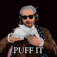 a man wearing headphones and a scarf says " puff it "