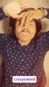 a man wearing a black shirt with white dots is making a funny face with his hands on his face