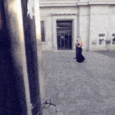 a woman in a black dress walks in front of a building with the number 242 on it