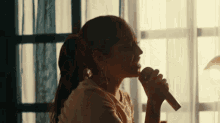 a woman in a ponytail is singing into a microphone .