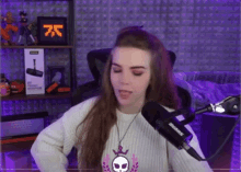 a woman wearing a shure microphone stands in front of a purple wall