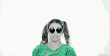 a woman in a green shirt and sunglasses is dancing .
