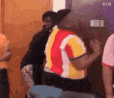 a man in a red and yellow shirt is standing next to another man in a yellow and white shirt .