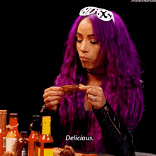 a woman with purple hair is holding a piece of food in her hands