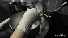 a person wearing white gloves is mixing something in a mixer that is made in animatica