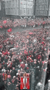 a crowd of people are gathered in front of a building with a trophy that says ' champions league ' on it