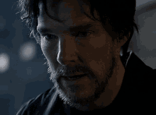 a man with a beard and a black shirt is looking at the camera