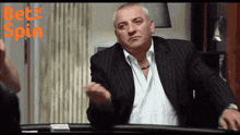 a man in a suit and white shirt is standing in front of a table with the words better spin written on the bottom