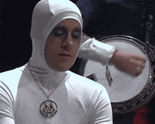 a man wearing a white hooded sweatshirt and a necklace that says gemini