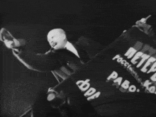 a black and white photo of a man holding a banner that says ' russia ' on it