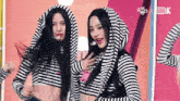 two women are standing next to each other wearing striped shirts with a hood .