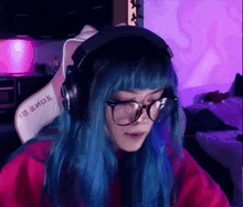 a woman with blue hair and glasses is wearing headphones and a red shirt .