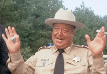 a man in a sheriff 's uniform is waving his hands