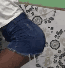 a woman wearing shorts and a white shirt is standing on a tile floor .