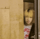 a man with yellow hair is peeking out from behind a wooden wall .