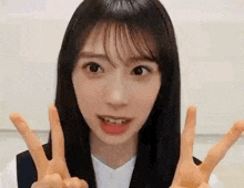 a close up of a young woman giving a peace sign with her hands .