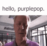 a man in a purple shirt is standing in a room with the words hello purplepop written above him .