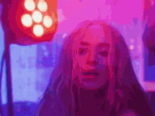 a woman with long pink hair is standing in front of purple lights