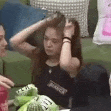 a woman is sitting on a couch holding her hair in her hand .
