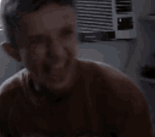 a young boy is laughing with his mouth open in a room .