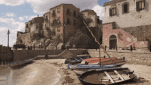 a row of boats are lined up on a sandy beach with a building in the background