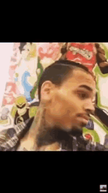a man with a tattoo on his neck is standing in front of a painting of a cartoon character .