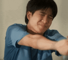 a man in a blue shirt is making a funny face with his eyes closed