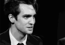 a man wearing a suit and tie smiles in a black and white photo