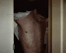 a shirtless man stands in a doorway with his eyes closed