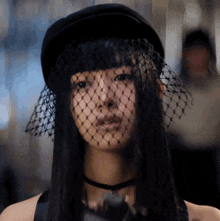 a woman wearing a veil and a hat looks at the camera