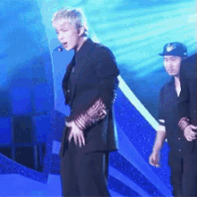 a man in a black suit is standing on a stage