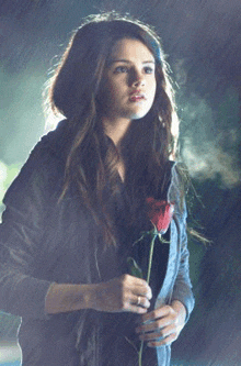 a woman holding a red rose in her hand