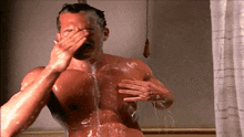 a shirtless man is taking a shower with his hand over his face