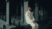 a man sits on a railing under a bridge with graffiti on it