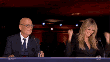 a man and a woman are sitting at a table with the nbc logo on the bottom