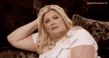 a woman wearing a tiara is laying on a couch with her hand on her head .