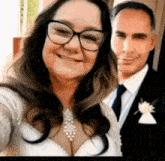 a bride and groom are posing for a selfie . the bride is wearing glasses and a necklace .